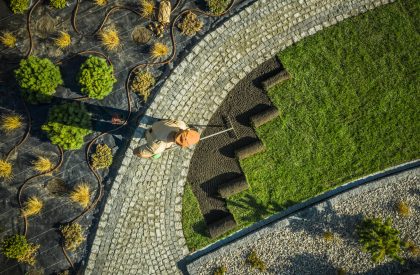 Gardener in Newly Build Backyard Garden Installing Natural Grass Turfs. Preparing Soil. Aerial View.